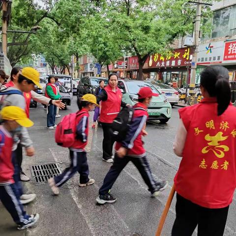 风雨中的坚守        指挥交通保安全 --------济水西街学校教师开展文明交通志愿服务活动